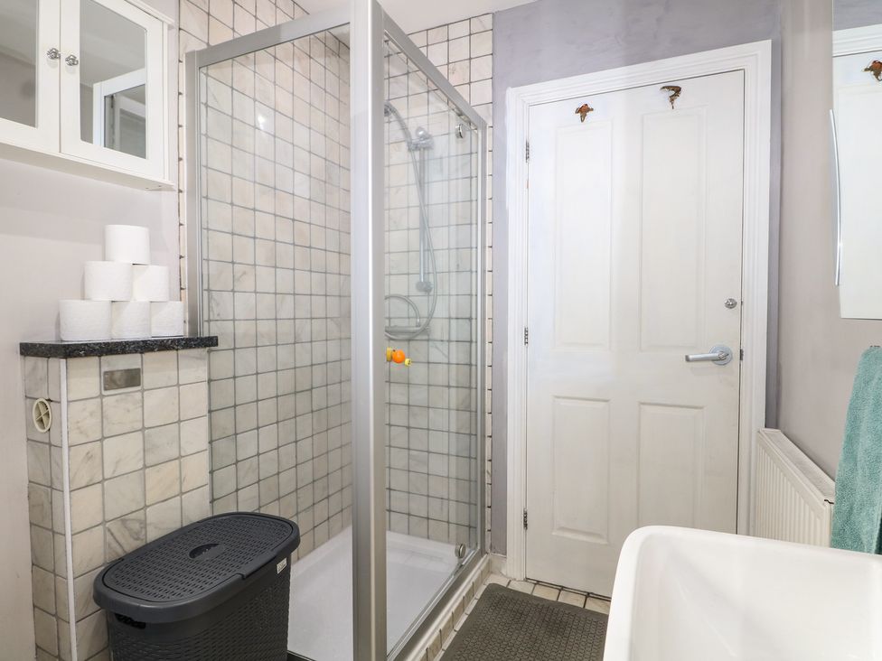 A bathroom with a shower and storage cabinet at Tiffanys Coach House in Bournemouth