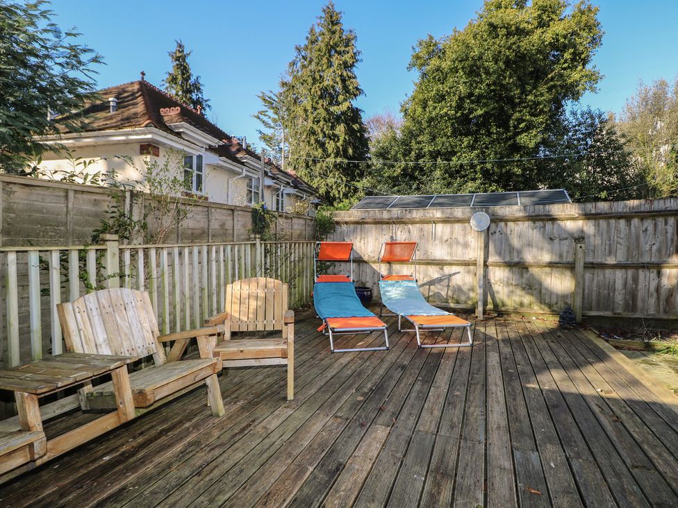 A garden with wooden chairs and deck chairs at Tiffanys Coach House in Bournemouth