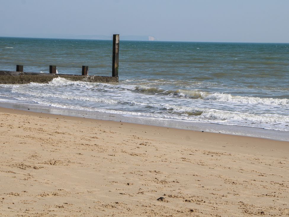 A beach with sand, water, and a pier at Tiffanys Coach House in Bournemouth