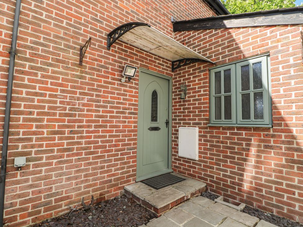 An entryway with a green door and brick wall at Tiffanys Coach House in Bournemouth
