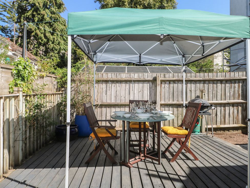 A garden with a table and chairs under a tent at Tiffanys Coach House in Bournemouth