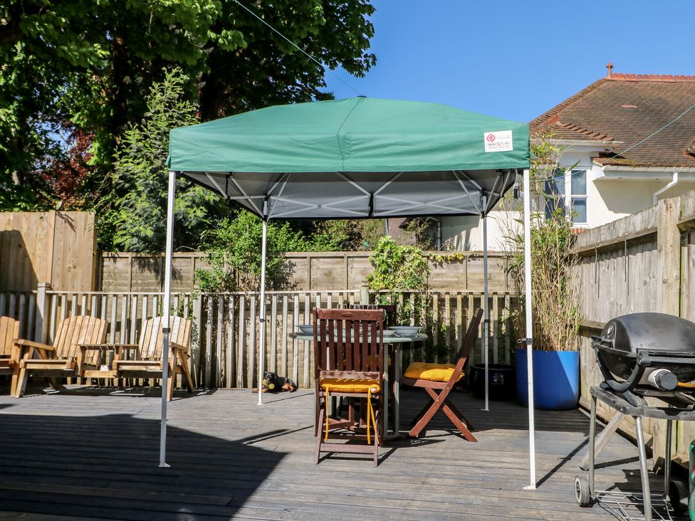 An outdoor area with a tent and wooden furniture at Tiffanys Coach House in Bournemouth