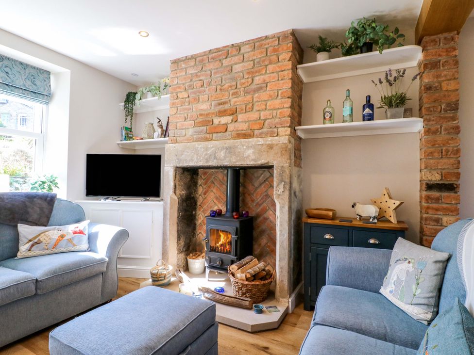 A living room with a fireplace and shelves at 7 Catcliffe Cottages in Bakewell