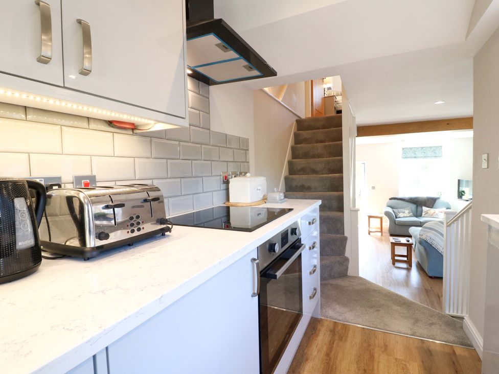A kitchen with appliances and a staircase at 7 Catcliffe Cottages Bakewell