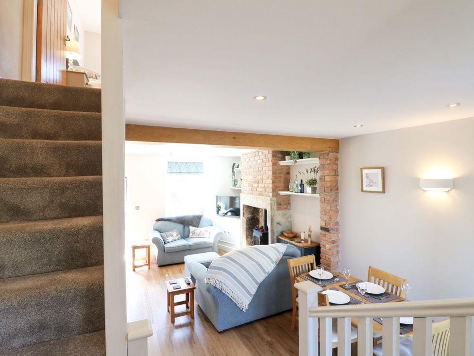 A living room with a staircase, seating area, and dining table at 7 Catcliffe Cottages, Bakewell