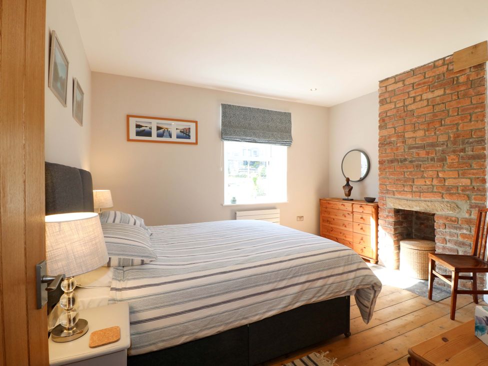 A bedroom with a bed, drawer unit, and fireplace at 7 Catcliffe Cottages Bakewell