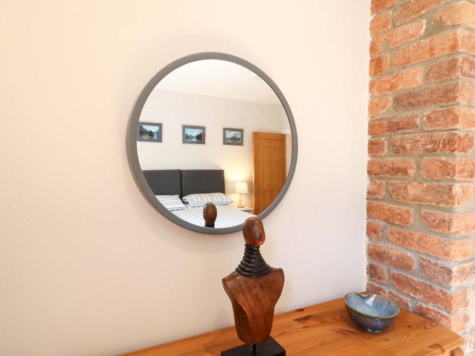 A bedroom with a mirror and wooden statue at 7 Catcliffe Cottages in Bakewell