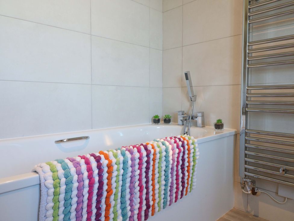 A bathroom with a bathtub and towel rack at 7 Catcliffe Cottages in Bakewell