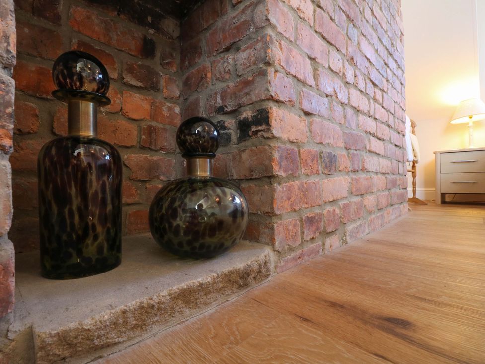 A living room featuring glass bottles on a shelf and a lamp at 7 Catcliffe Cottages in Bakewell