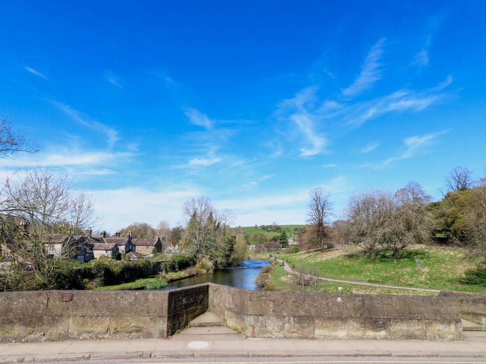 A view of a river and bridge with houses and trees at 7 Catcliffe Cottages Bakewell