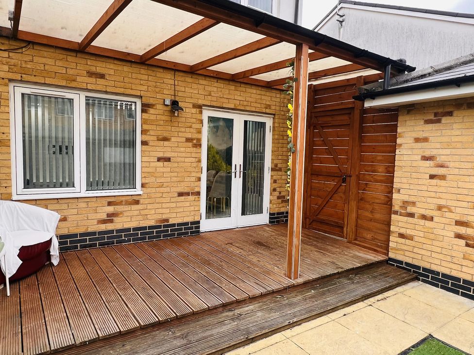 An outdoor area with a wooden deck and sliding doors at Fairclough Close Northolt