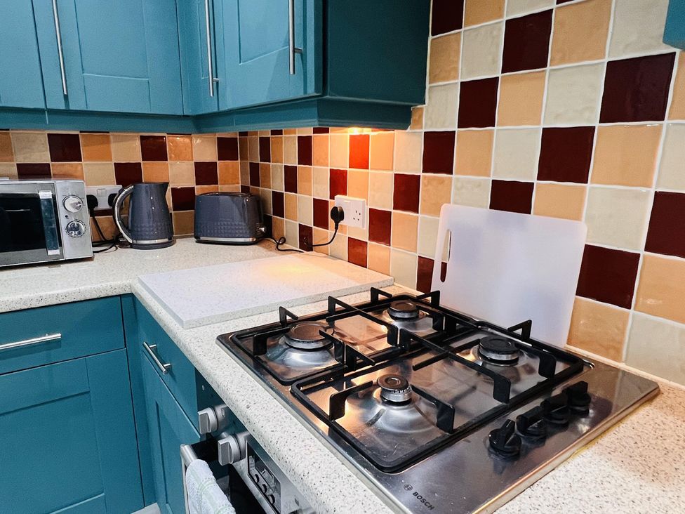 A kitchen with a gas stove and microwave at Fairclough Close in Northolt