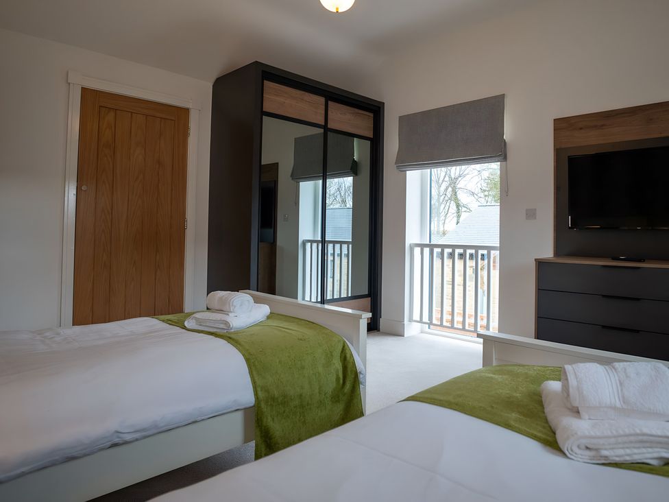 A bedroom with two beds and a wardrobe at The Galloway in Morpeth