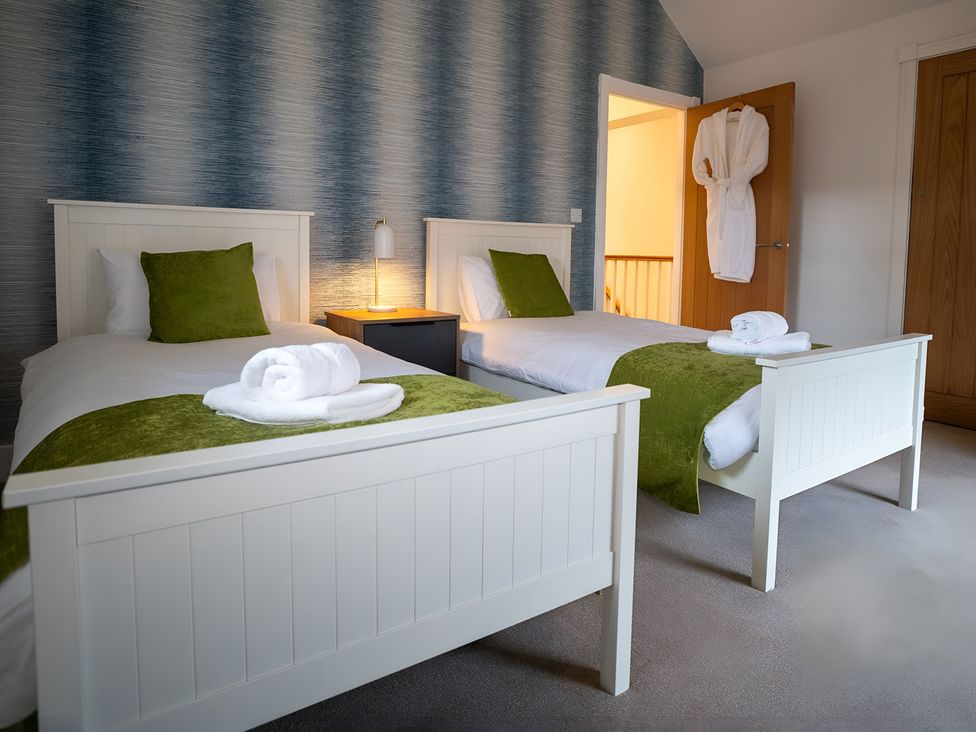 A bedroom with two beds, a nightstand, and a robe at The Galloway in Morpeth
