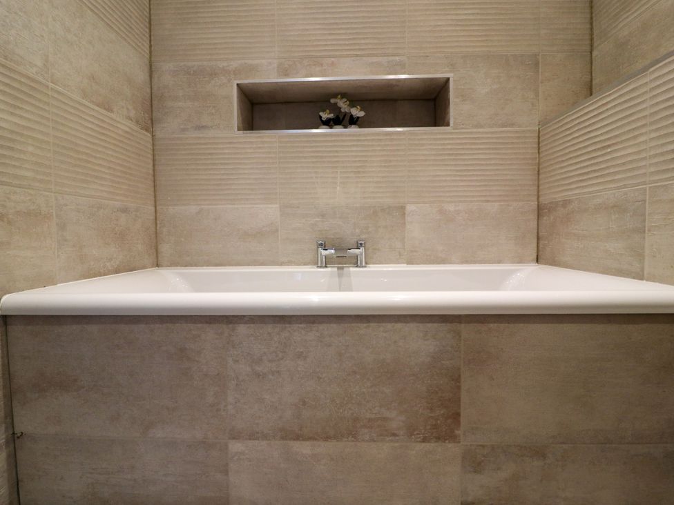A bathtub with faucet and decorative plant in a bathroom at The Newland in Morpeth
