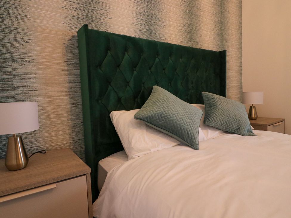A bedroom with a green headboard and pillows at The Newland in Morpeth