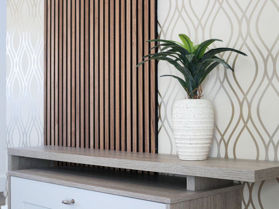 A living room with a plant in a vase on a shelf at The Newland in Morpeth