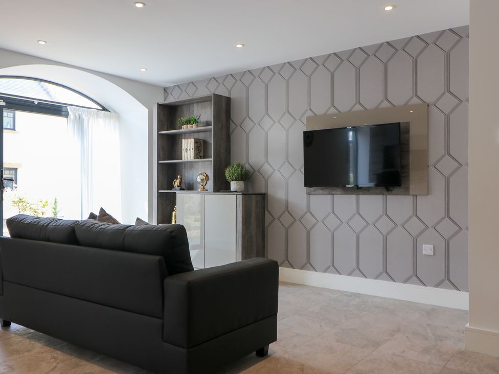 A living room with a sofa and a television on the wall at The Gavel in Morpeth