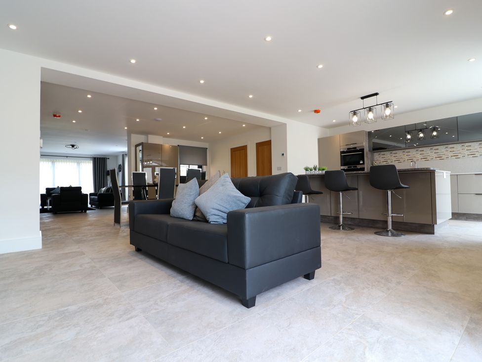 A living room with a black couch and kitchen area at The Gavel in Morpeth