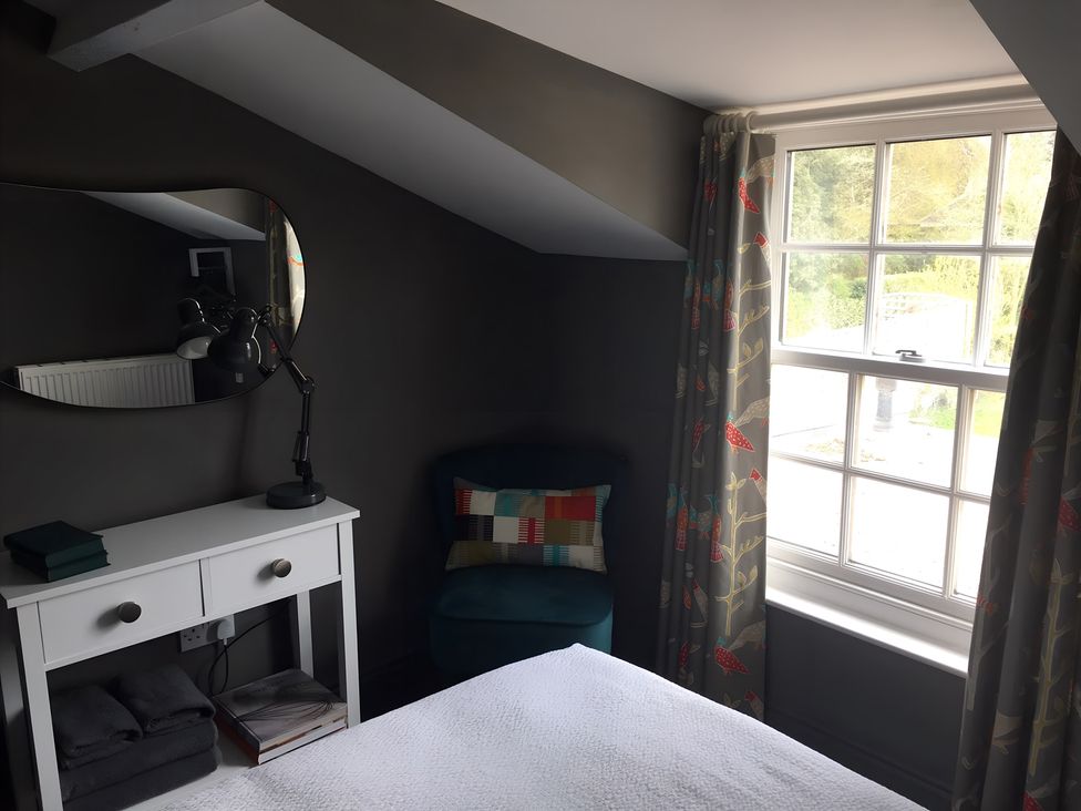 A bedroom with a table, chair, lamp, and curtains at 29 Front Street Market Rasen