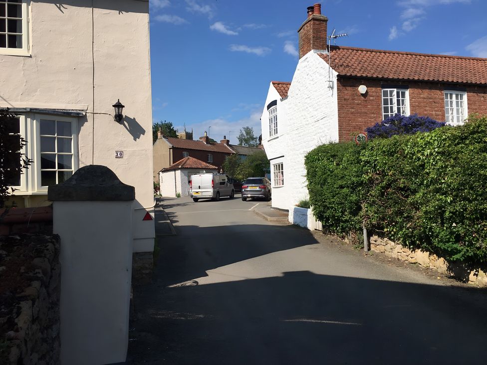 A street view with buildings and parked vehicles at 29 Front Street in Market Rasen