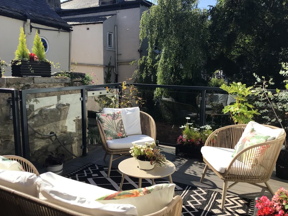 An outdoor terrace with seating and plants at Honeysuckle Lodge in Knaresborough