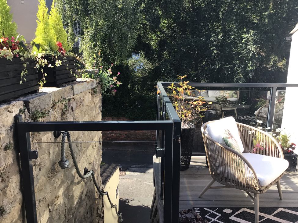 An outdoor seating area with a chair and planters at Honeysuckle Lodge in Knaresborough
