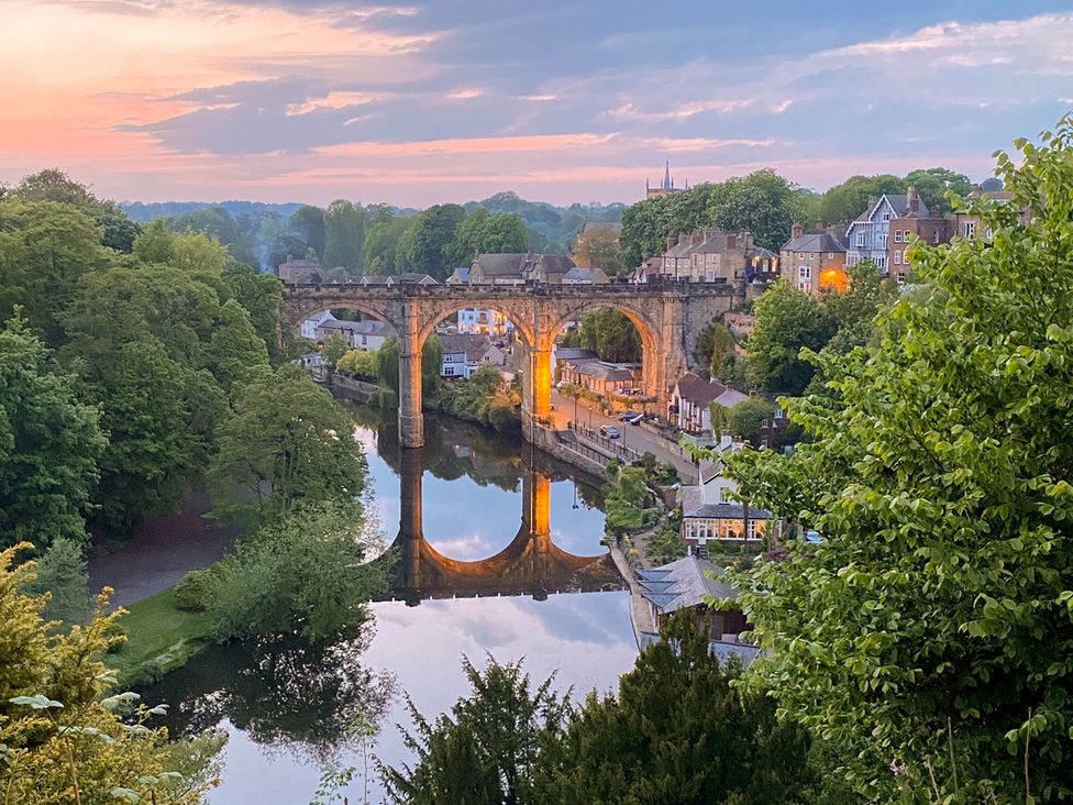 A view of a bridge over water with buildings and trees at Honeysuckle Lodge in Knaresborough