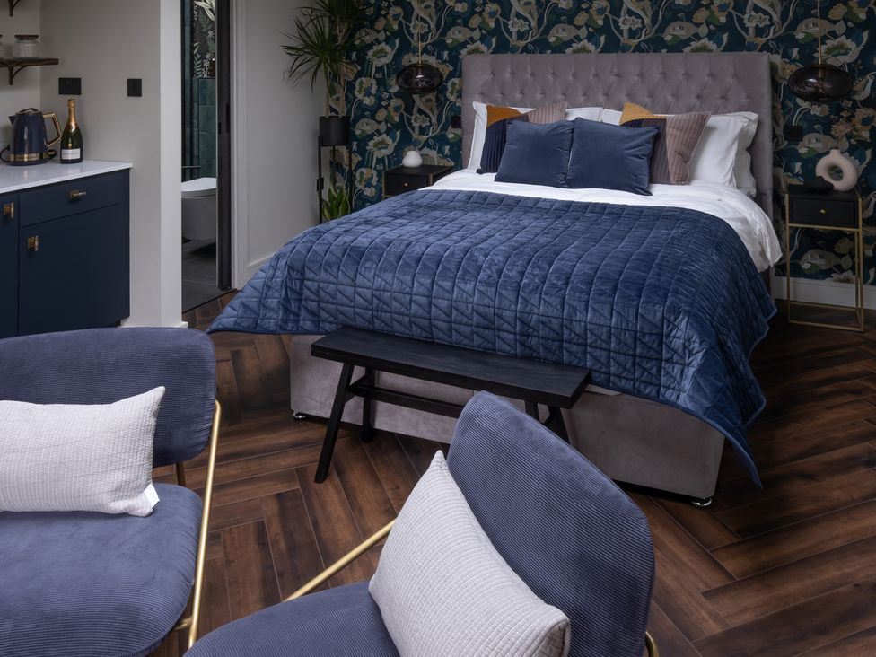 A bedroom with a bed and chairs at Honeysuckle Lodge in Knaresborough