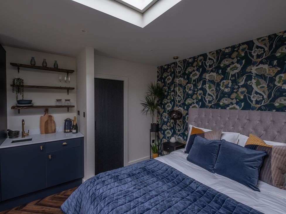 A bedroom with a bed and kitchenette at Honeysuckle Lodge in Knaresborough