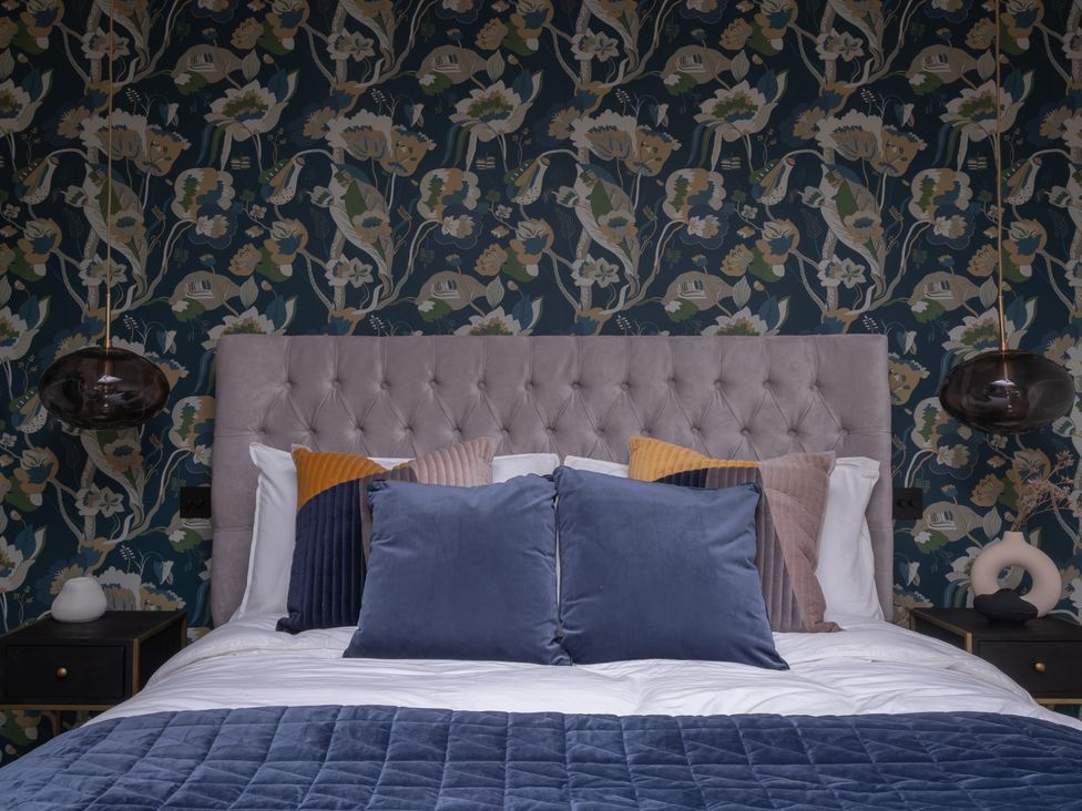 A bedroom featuring a bed with pillows and a decorative wall at Honeysuckle Lodge in Knaresborough