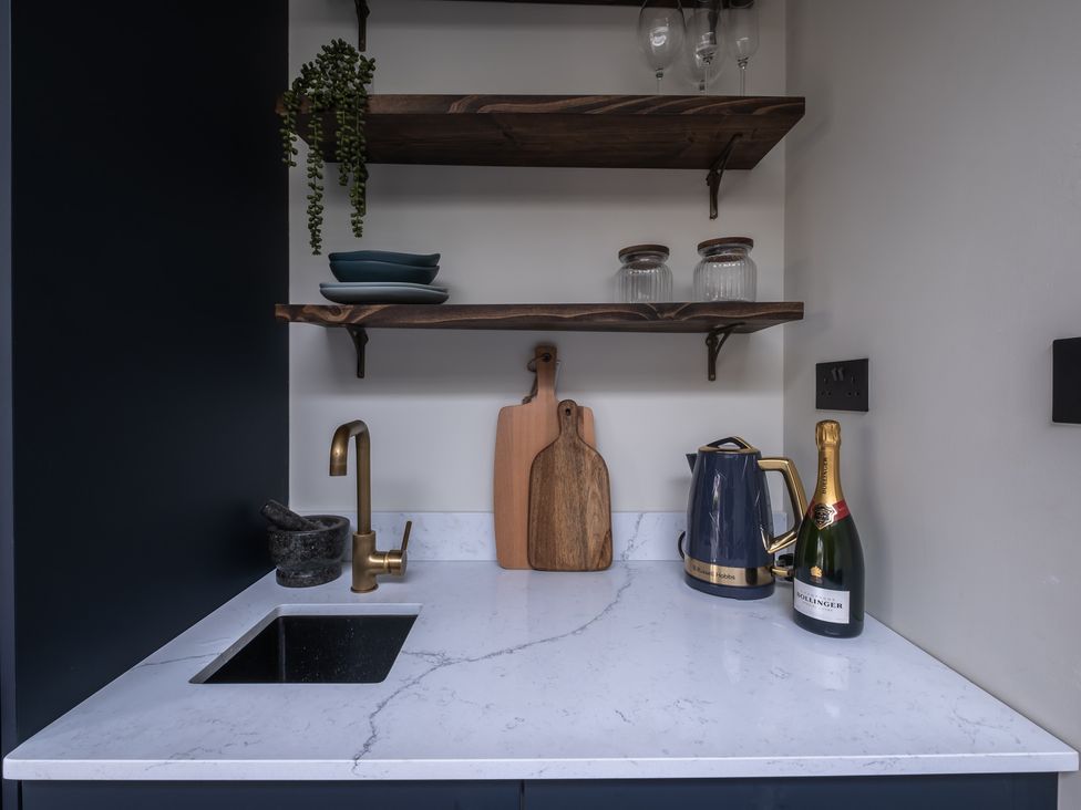 A kitchen with a sink and shelves at Honeysuckle Lodge Knaresborough