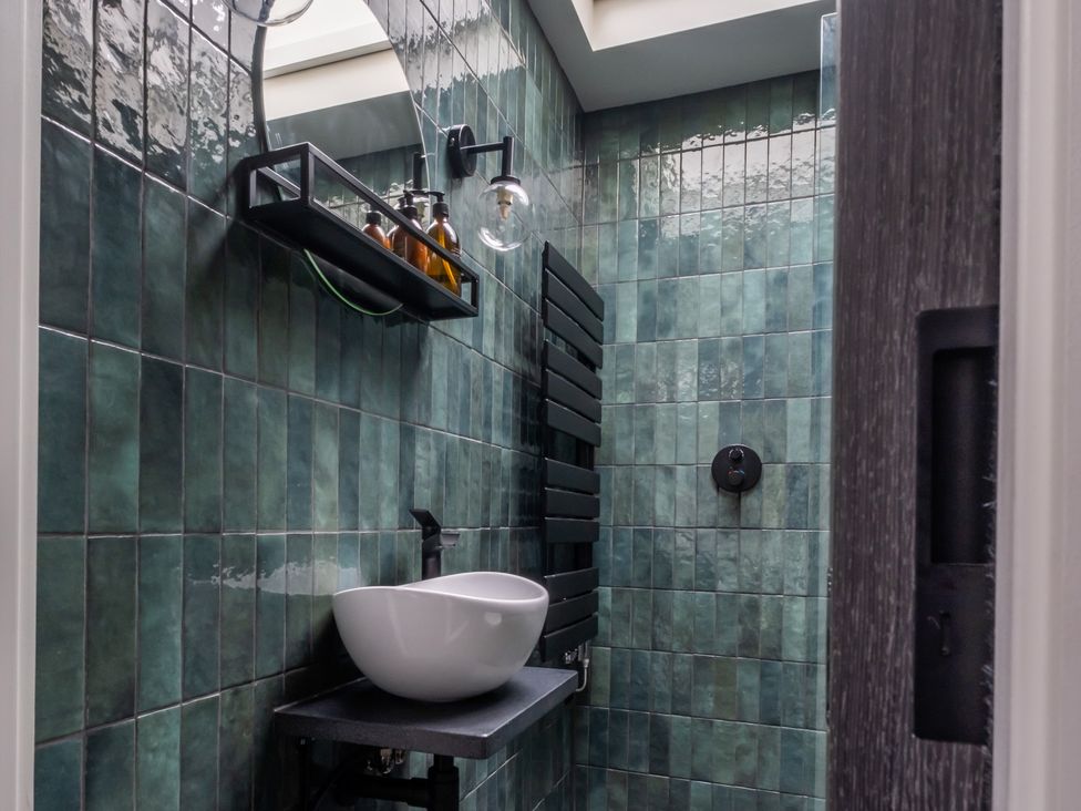 A bathroom with a sink and shelf at Honeysuckle Lodge in Knaresborough