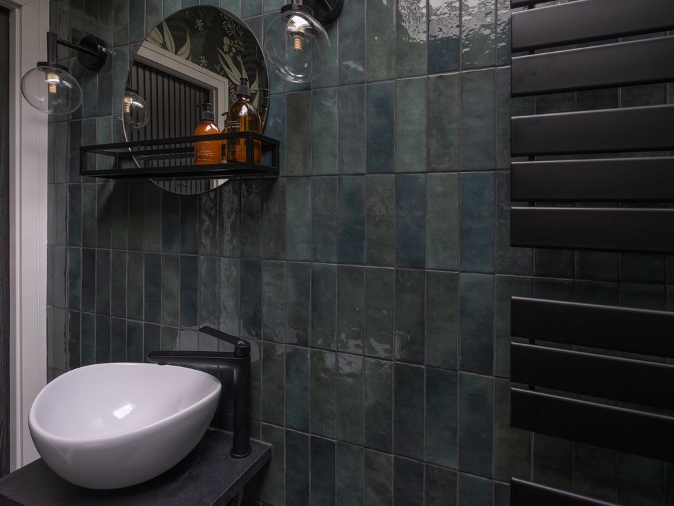 A bathroom with a wash basin and mirror at Honeysuckle Lodge in Knaresborough
