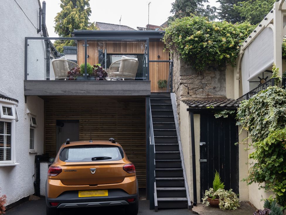 An outdoor view of a car and stairs leading to a deck at Honeysuckle Lodge in Knaresborough