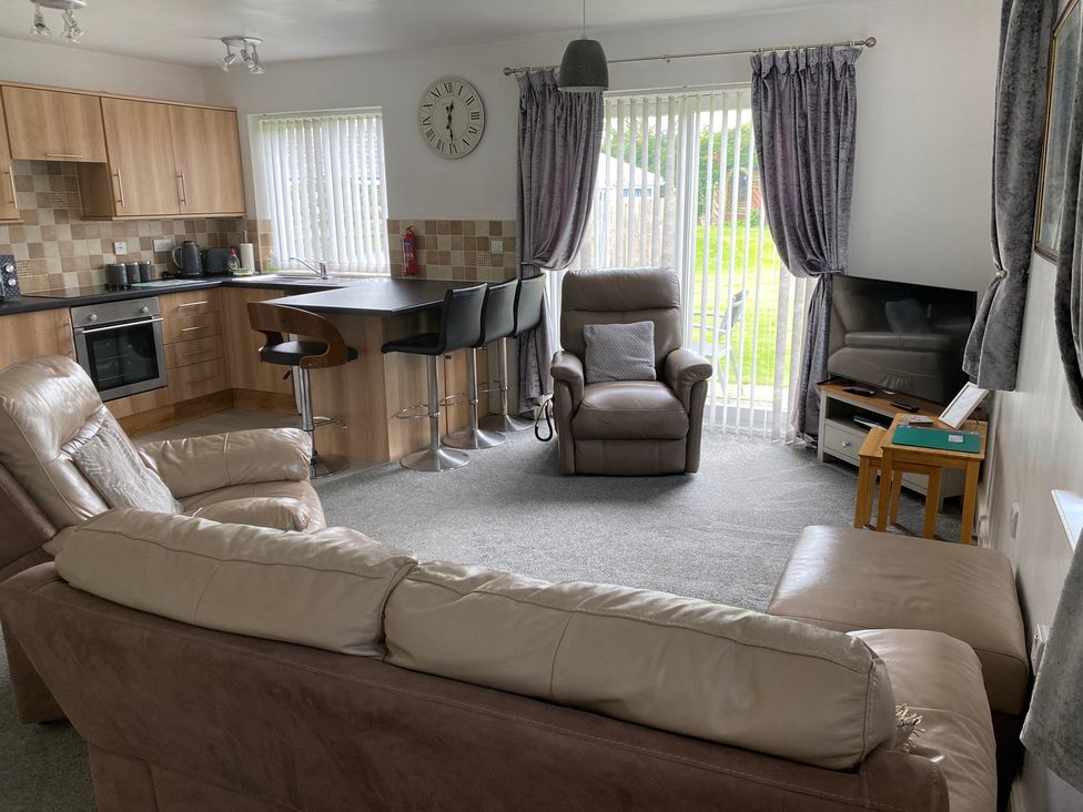 A living room with a sofa and kitchen area at 19 Carnaby Mews in Bridlington