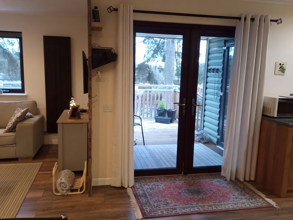 A living room with a sofa and door leading to a deck at Gowrie Lodge in Blairgowrie