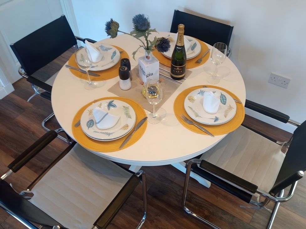 A dining table set with plates and glasses at Gowrie Lodge in Blairgowrie