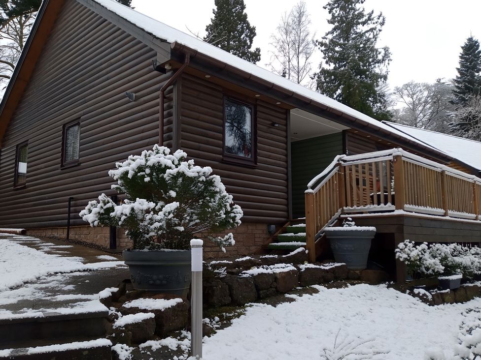 A house with a deck and planters in the snow at Gowrie Lodge in Blairgowrie