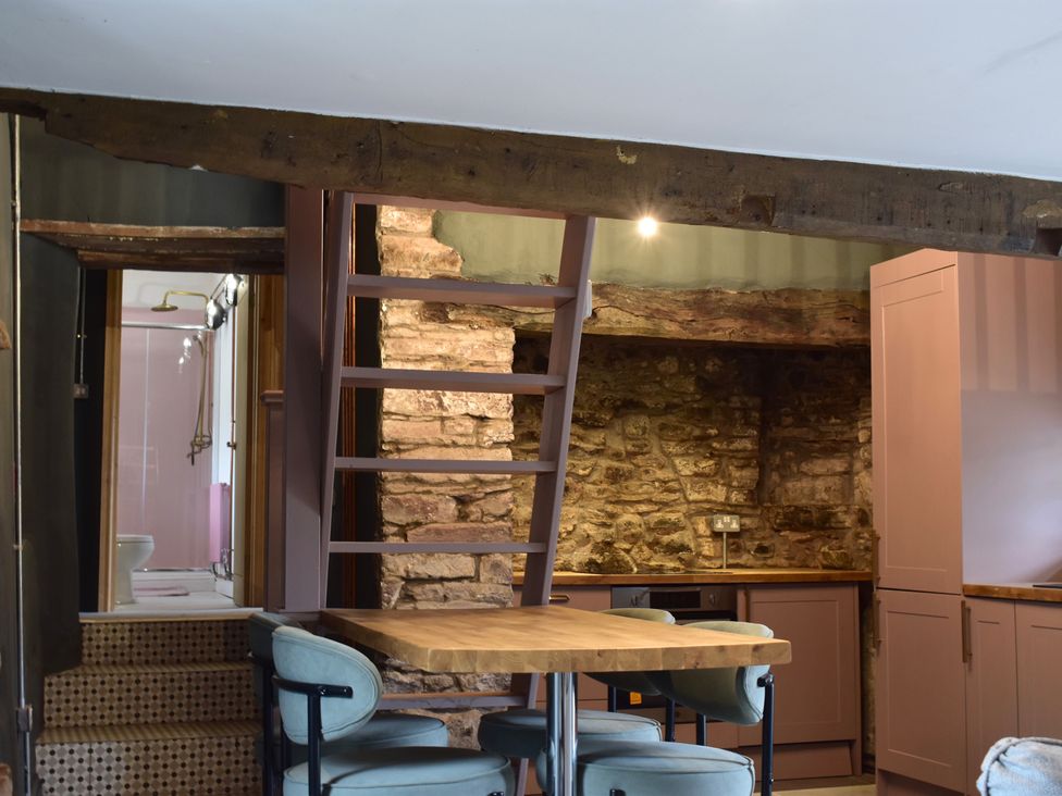 A kitchen with a staircase and stone wall at Ty Llaeth in Carmarthen