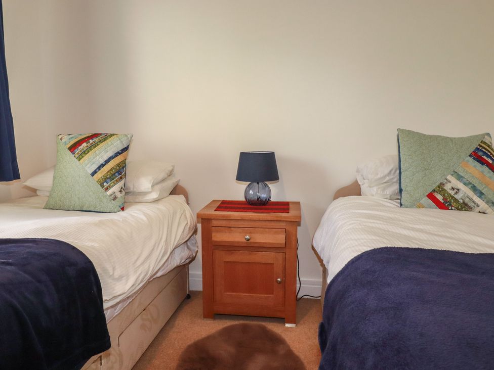 A bedroom with two twin beds and a bedside table at Treveline in St Mabyn