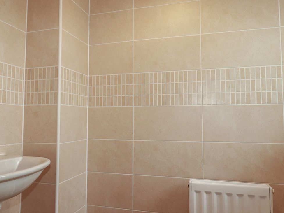 A bathroom with a sink and tiled wall at Treveline St Mabyn