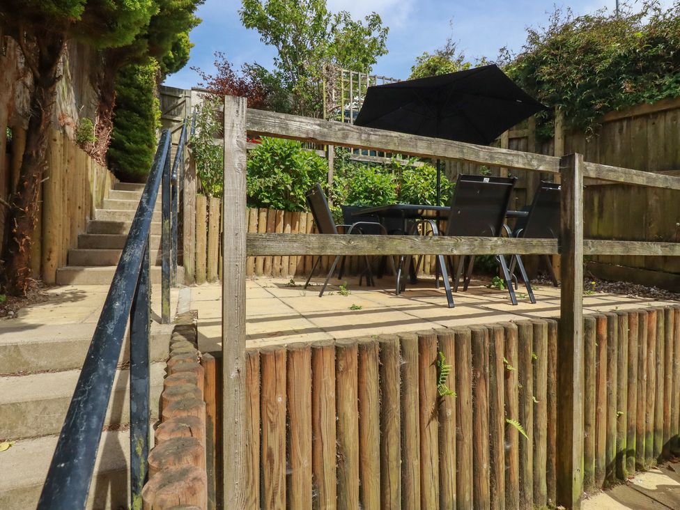 A garden area with a table and chairs under an umbrella at Treveline in St Mabyn
