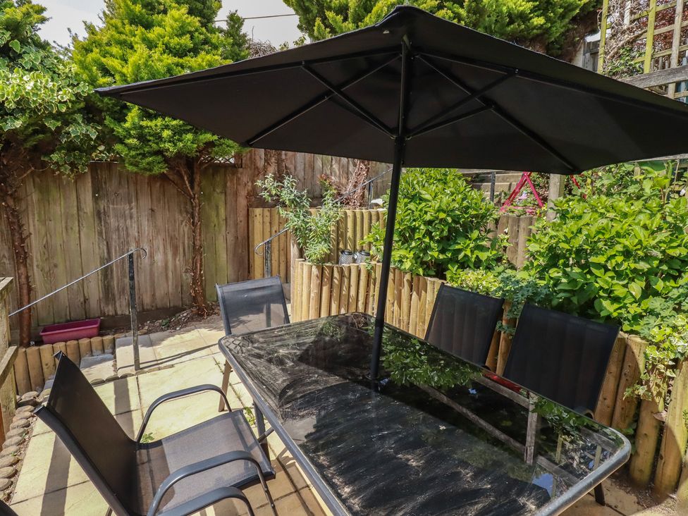 A garden setup with a table and chairs under a parasol at Treveline in St Mabyn
