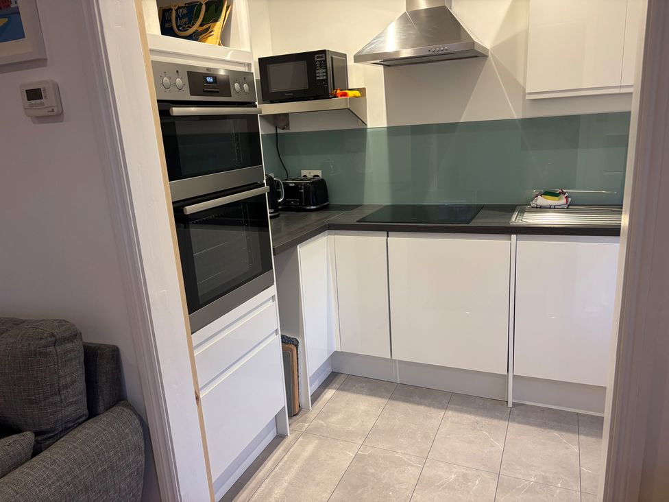A kitchen with an oven, microwave, kettle, cooktop, and sink at Edal Court in Sheringham