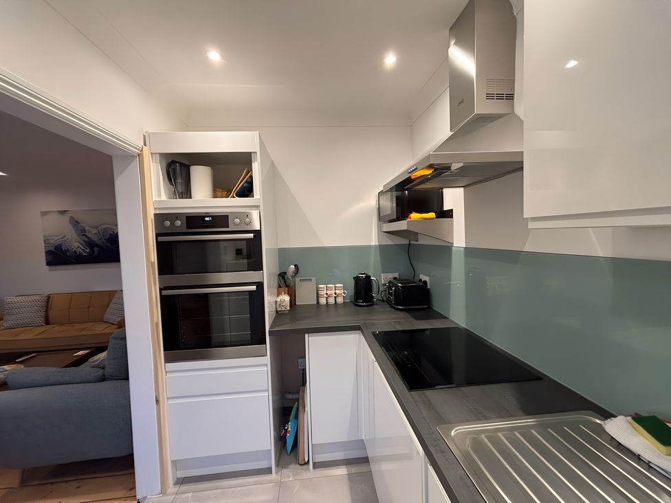A kitchen featuring an oven, microwave, kettle, and sink at Edal Court Sheringham