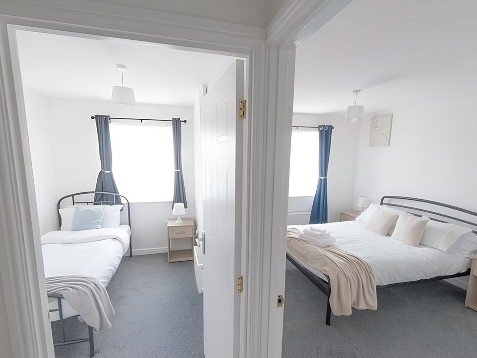 Two bedrooms with beds and nightstands at Bluebell Close in Corby
