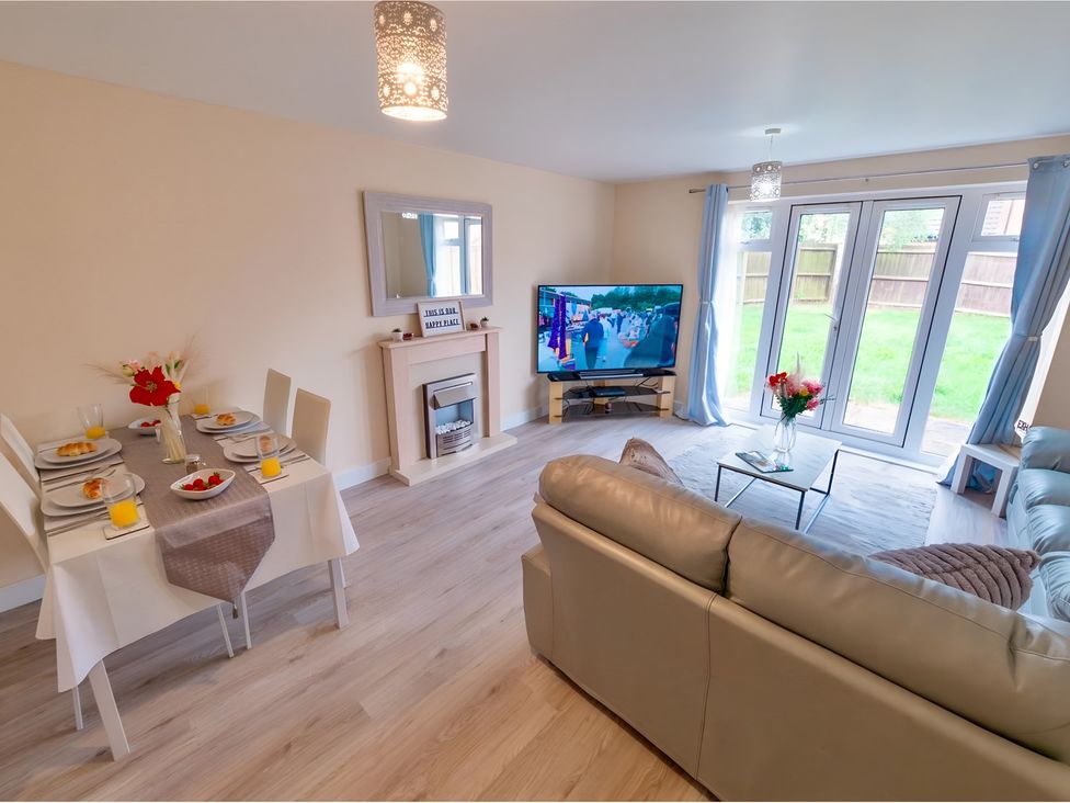 A living room with a dining table and television at Rochester Road in Corby