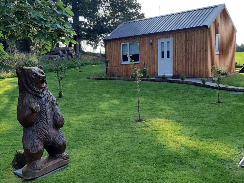 A garden with a wooden cabin and a bear statue at Taigh Nam Moireach in Inverness