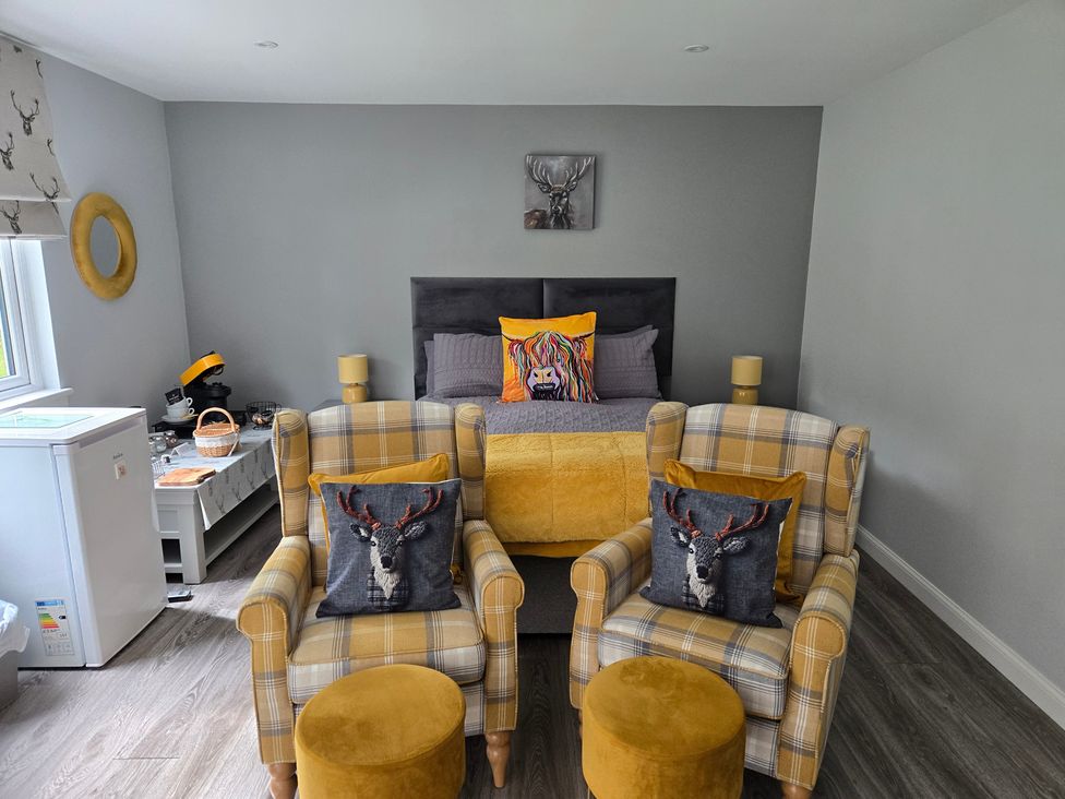 A bedroom with a bed and chairs at Taigh Nam Moireach in Inverness